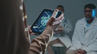 Tanımlanamayan kadın eczacılık satış temsilcisinin, yeni ilaç veya terapiyi konferansta doktorlara tanıtan tablet bilgisayarında sunum slaytıyla orta ölçekli yakın çekimi.