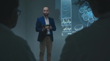 Orta Doğulu erkek ilaç satış temsilcisi, yeni ilaç ya da terapiyi konferansta doktorlara sunan tablet bilgisayarla tam omuz hizasında.