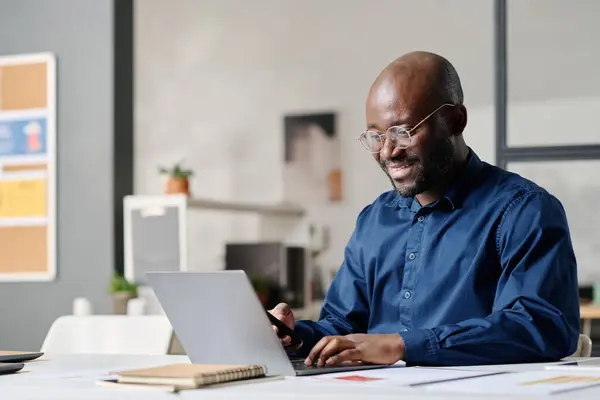 Stock image Young African American manager typing on laptop at work in modern office, medium shot, copy space