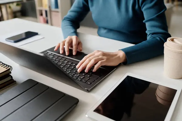 stock image High angle of hands of unrecognizable woman sitting at desk typing on laptop at workplace in modern office