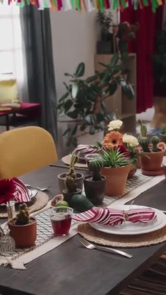 クローズアップアーク垂直 誰もゼラベラの花 サボテン プレート 4人のためのカトラリーと椅子で装飾されたメキシコの家庭でお祝いのディナーテーブルを撮影しません 休日の祝いの準備ができて — ストック動画