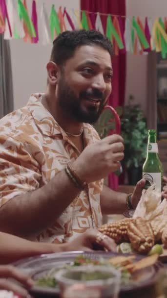 五月宫假期期间 穿着花纹衬衫的墨西哥大胡子男子与朋友坐在餐桌旁 拿着啤酒和辣椒 说笑话 这段中等垂直镜头让人捧腹大笑 — 图库视频影像