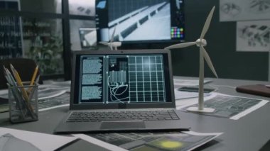 Yel değirmeni modelinin yanındaki dizüstü bilgisayarda ve modern temiz enerji departmanının ofisindeki masada görünen güneş pili görüntüsü yok.