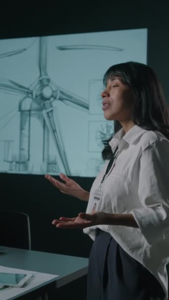 女性拉美裔创新者向合作伙伴展示新型风力涡轮机转子叶片的侧向垂直镜头 并在会议上指向蓝图图像 — 图库视频影像