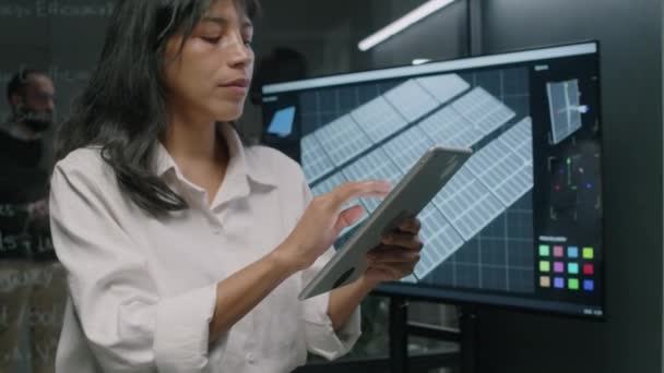 在可再生能源部门 女性西班牙工程师在工作日将有关光伏电池的数据输入数字平板电脑查看太阳能电池板模型的侧拉出画面 — 图库视频影像