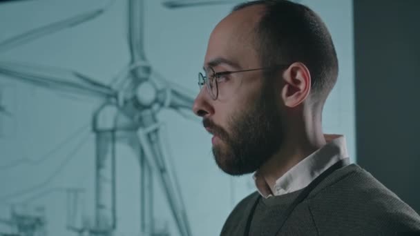 男性玻璃杯风力发电工程师的侧斜镜头 并在室内会议期间向观众展示风车生产行业的进展情况 — 图库视频影像