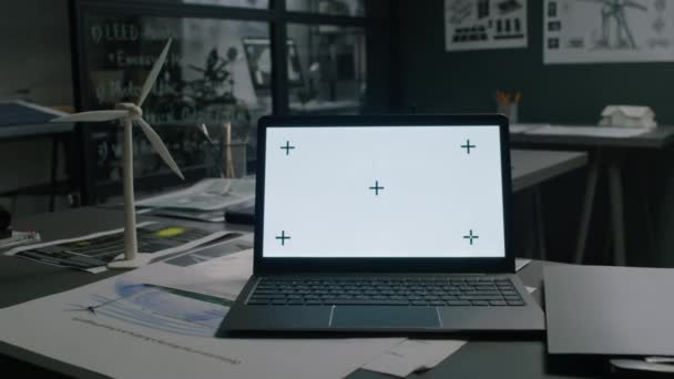複数の図面と青写真を持つクリーンエネルギー工学部オフィスのテーブル上の風力タービンプロトタイプの近くに白い染色体スクリーンを持つ無線ラップトップコンピュータの映像はありません — ストック動画