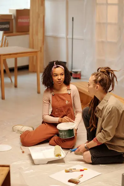 Two Young Intercultural Women Workwear Sitting Floor Cafe Refit Renovation Stock Picture