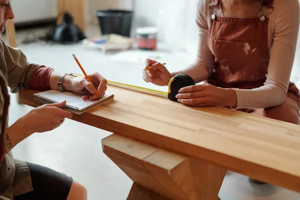 Two Young Women Workwear Sitting Bench Taking Its Measures While Royalty Free Stock Images