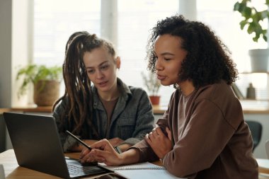 Genç kendinden emin Afrikalı Amerikalı bayan girişimci, iş yerindeki online verilerin tartışılması veya sunumu sırasında dizüstü bilgisayara işaret ediyor