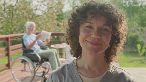 머리를 코카서스 여성의 클로즈업 초상화 시설의 정원에서 카메라에 배경에 휠체어에 — 비디오