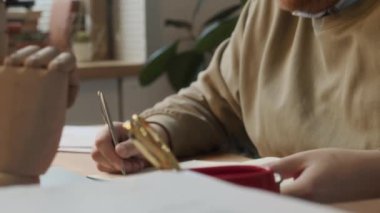 Orta pişmiş, beyaz tenli, gözlüklü, kırmızı kıvırcık saçlı, rapor üzerinde çalışan, kahvesini yudumlayan, konsantre olmaya çalışan, dikkati dağılmış ve top ile hokkabazlık yapan bir erkek şirket çalışanı.