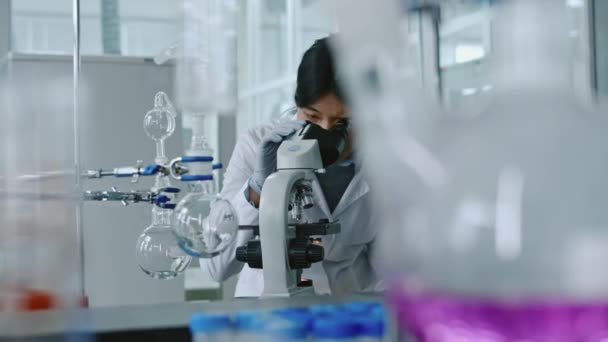 手套弯腰 显微镜观察 镜片放大镜调整及样品研究中的中位中国女研究人员 — 图库视频影像