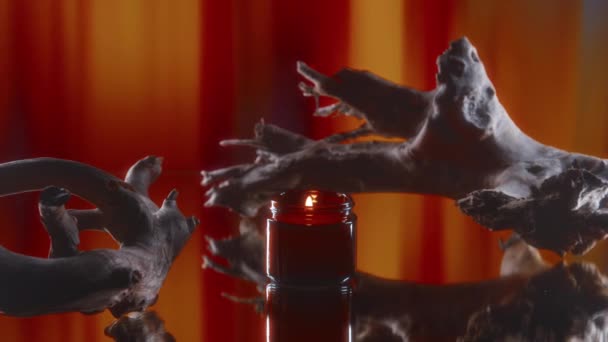 没有人在漂泊木附近的红色玻璃瓶中近距离点燃香气蜡烛 在红色抽象条纹的背景下营造出浪漫的气氛 — 图库视频影像