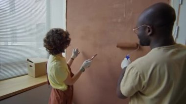 Mutlu eşlerin arka görüntüleri yenilenmiş apartman duvarlarını boyamayı bitirir ve beşlik çakar