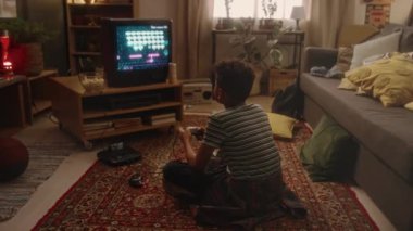 Sadece evdeki retro konsolda, 90 'lardaki nostaljik çocukluk atmosferinde tutkulu bir şekilde yerde oturan ve uzay nişancısı video oyunu oynayan bir çocuğun tam görüntüsü.