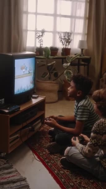 上世纪90年代 两个不同的男孩坐在电视机前的地板上 在复古风格的家中玩老式街机游戏 — 图库视频影像