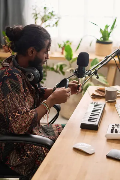 若いクリエイティブな男は ホームスタジオで職場に座って 新しい音楽を作ったり演奏したりする前にサウンドレコーディング機器を固定します ストックフォト