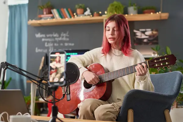 かわいいティーンエイジャーの少女はマイクの前に椅子に座って 新しい歌を演奏し ホームスタジオでアコースティックギターを演奏 ロイヤリティフリーのストック写真