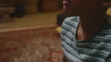 Eski oturma odasında patlamış mısır yiyen ve dikkatle retro film izleyen Afrikalı Amerikalı bin yıllık çocuğun yan çekimleri.