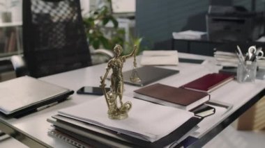 Hukuk bürosundaki ofis masasında bronz kadın heykelciğinin görüntüsü yok.