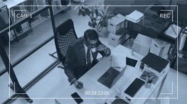 Üst düzey kamera görüntüleri, modern ofisteki bir masada dizüstü bilgisayar üzerinde çalışırken takım elbiseli ve gözlüklü yaşlı erkek avukatın espresso içtiğini gösteriyor.