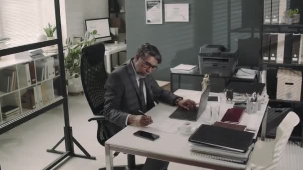 现代律师事务所工作期间 男性律师在笔记本电脑上工作并在文件中做笔记的弧形镜头 — 图库视频影像