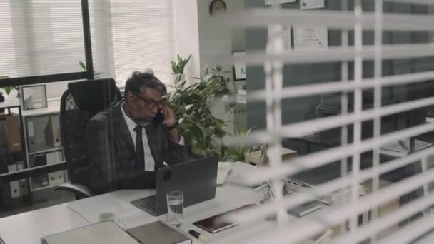 経験豊富なBiracialバリスターのガラス映像を通じて オフィスで法的文書を作成する顧客との電話会話 — ストック動画