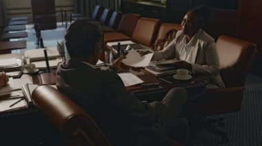 Kimliği belirlenemeyen erkek hukuk firmasının CEO 'su, siyah kadın hukuk çalışanından belge alıp toplantı odasında kontrol ederken görüntüler.