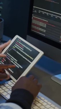 Bilgisayar ekranı ve tablette mobil uygulama için kod üzerinde çalışan tanınamayan çoklu etnik yazılım geliştiricilerinin ellerinin dikey görüntüsü, hata veya hata tartışması