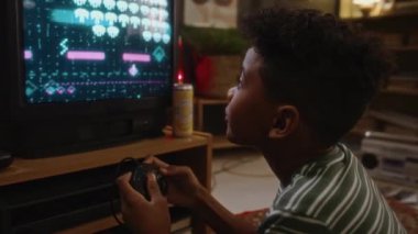 Afro-Amerikan milenyum çocuğunun göğüs kafesi tutkulu bir şekilde TV 'de 2 boyutlu oyun konsolu oynarken evde tek başına, nostaljik 90' ların atmosferinde