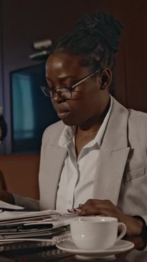 Afrika kökenli Amerikalı kadın avukatın konferans salonunda oturup belgelerle çalışırken, kağıtlarla notlar alırken, Kafkasyalı meslektaşı geçerken...