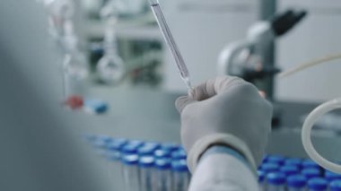 Anonim teknisyenlerin eldiven giyip pipetten deney tüpüne sıvı dökerken teşhis laboratuarında testler yaparken çekilmiş yakın çekim görüntüleri.