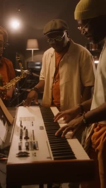 レコーディングスタジオでシンセサイザーに立っている2人の黒人男性ミュージシャンの中央垂直 キーボードでコードを演奏しながら 新しいアルバムのための曲を作曲 — ストック動画