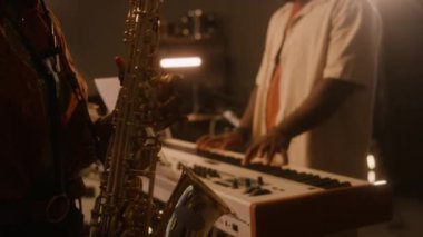 Tanınmayan Afro-Amerikan kadın mercekli, saksafon çalan, klavye ve davul çalan, stüdyoda ya da kulüp konserinde birlikte şarkı söyleyen siyahi erkekler.