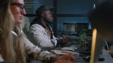 İki farklı programcının gece geç saatlerde ofiste bilgisayar kodları yazması, yorgun Afrikalı Amerikalı genç bir adamın kaslarını esnetmesi, hassas gözlerini ovuşturması ve sonra işe geri dönmesi.