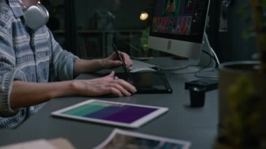 Orta bölüm ve evde bilgisayarla birlikte stüdyoda oturan, ticari resimler ya da görüntüler üzerinde çalışan, Stylus kalem ve dijital grafik tabletle çizim yapan kadın serbest rötuşçunun elleri.