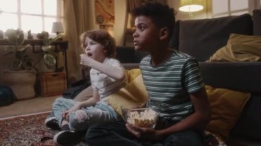 Ebeveynler işe giderken iki farklı çocuğun yerde patlamış mısırla oturup korku filmi izlediği beyaz çocuğun gözlerini kapattığı ve siyahi çocuğun 90 'lı yaşlarda ekranı işaret ettiği yan görüntüler.