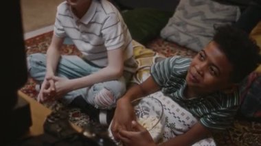 Televizyonda film izleyen ve evde patlamış mısır yerken gülen iki neşeli çocuğun el kamerasıyla çekilmiş görüntüleri. 90 'larda tasasız bir nostaljik çocukluk dönemi.