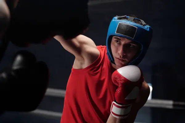 Joven Boxeador Con Casco Protector Mirando Rival Pateándolo Durante Ataque — Foto de Stock