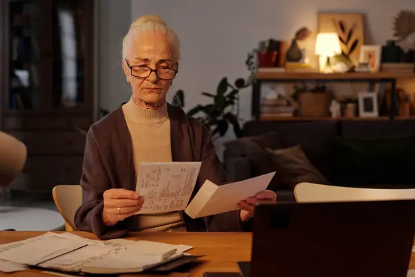 Donna Anziana Con Gli Occhiali Che Prende Fattura Finanziaria Piegata Fotografia Stock