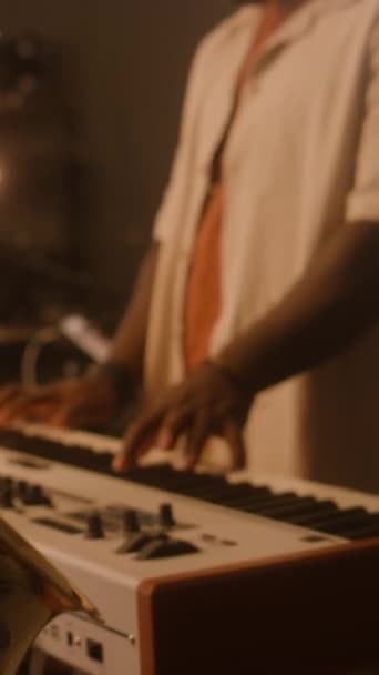 キャップにアフリカ系アメリカ人男性の中央垂直スローモ キーボードでコードを演奏するサングラス ドラムでバンドメイト スタジオで一緒にリハーサル — ストック動画
