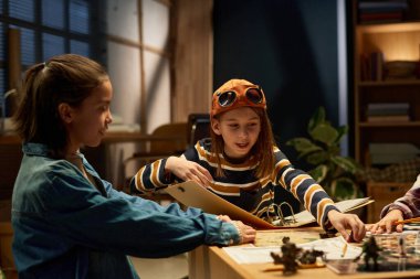 Boş zamanlarında arkadaşlarıyla oynarken karakter figürleriyle birlikte çip üzerinde gezinen açık klasörlü genç oyun lideri