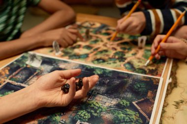 Yeni oyun tahtası üzerinde zar grubunu tutan tanınmamış bir gencin eli. Birkaç arkadaşın önünde masanın başında otururken.