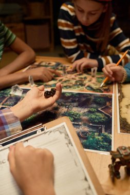 Masa başı oyunu sırasında sihirli ormanın resmiyle onları tekneye atmadan önce zar grubunu tutan genç bir kızın eli.