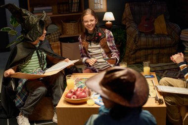 Masaüstü oyununda gülen sevimli, neşeli bir kız. Kültürler arası arkadaşların arasında oturmuş karakterlerinin kostümlerini giyiyor.