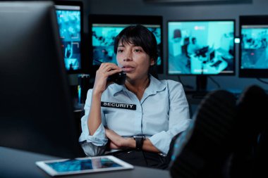 İş sırasında bilgisayar ekranına bakarken, üniformalı ciddi kadın polis telsizle durumu bildiriyor.