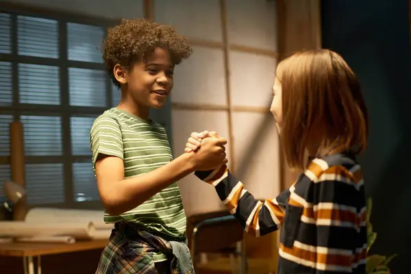 stock image Happy African American boy in striped t-shirt looking at his buddy and shaking his hand while both greeting one another