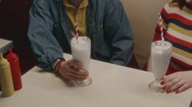Kafkasyalı genç adam ve kızın akşam kafede milkshake içerken utanarak el ele tutuşmaları.