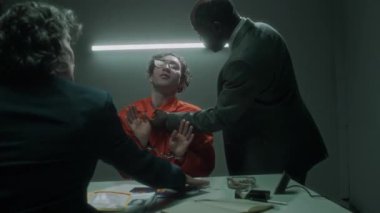 Kaba sorgulama sırasında kızgın Afrikalı Amerikalı erkek dedektifin terörü boğazından yakalayıp sallaması beyaz kadın ortağın müdahale etmesi, tutuklu gülüşü.